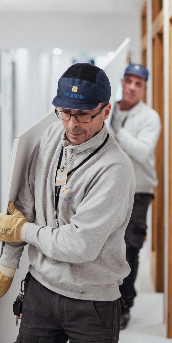 Monteurs qui transportent une planche de bois.
